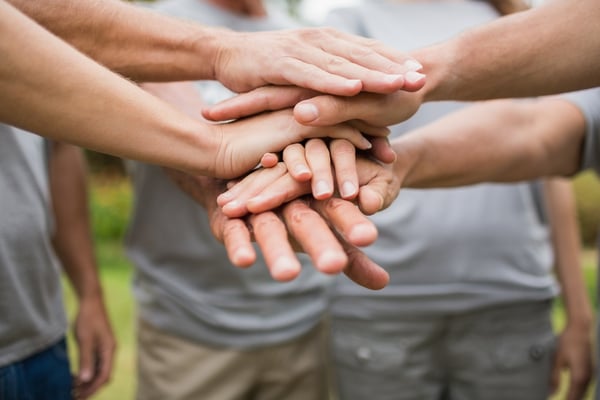 Personas poniendo sus manos juntas para trabajar en equipo